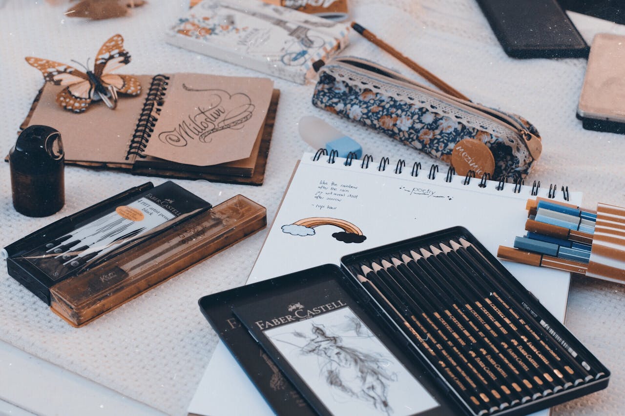 Art supplies including pencils, pens, and sketchbooks arranged on a table for creativity.