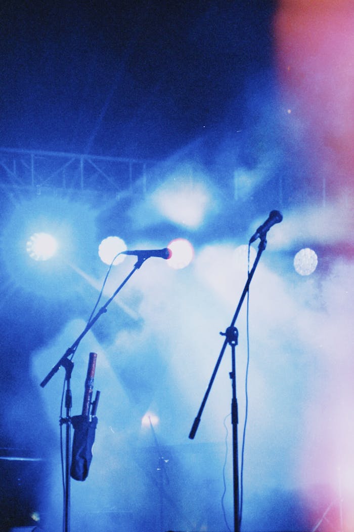 Energetic concert stage in Almaty, featuring colorful lights and microphones amidst smoke effects.